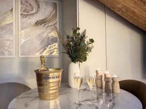 圣艾蒂安Cocon Blanc câlin - Jacuzzi privatif - Love Room à Saint Etienne的一张桌子,上面放着一瓶香槟和两杯酒杯