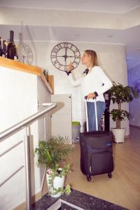 米兰Hotel Fioralba的一位带着手提箱和时钟站着的女人