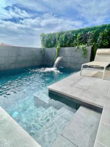 圣地亚哥港The Retreat House - Private Pool的一个带椅子和瀑布的游泳池
