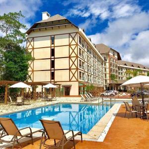 佩德拉阿祖尔Flat Pedra Azul - hospedagem nas montanhas的一座带游泳池和椅子的酒店和一座建筑