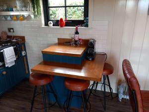 韦斯特波特Delightful Shepherds Hut的小厨房配有带凳子的桌子