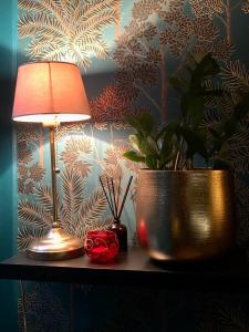 翁弗勒尔Reglisse et Pain d'Epices - Chambres d'hôtes的桌子上的一盏灯和一棵盆栽植物