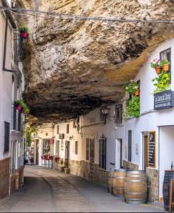 塞特尼尔Casa Rural Moreno的一条有石墙的小巷和有桶的建筑