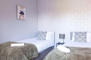 北安普敦Spacious Home - Ideal for Contractors的一间卧室配有两张带白色床单和灯的床