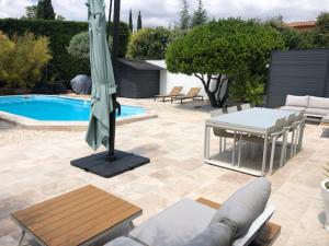 卡西斯L'arbousier的一个带桌子和遮阳伞的庭院和一个游泳池