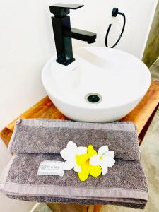 布韦朱Butterfly Apartment Zanzibar的浴室设有水槽和鲜花毛巾