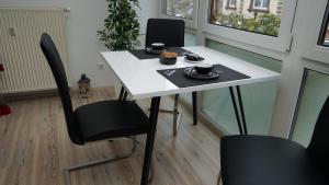 菲希特尔山区巴特贝内克Gemütliches Apartment in Bad Berneck的一张白色的桌子和椅子,上面有杯子和盘子