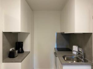 因斯布鲁克Gemütliche Wohnung mit Gartenblick的厨房配有白色橱柜和水槽