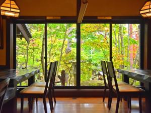 安昙野市Hotakajo的客房设有桌椅和大窗户。