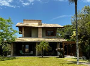 因比图巴Casa de praia no Rosa - vista para Lagoa de Ibiraquera的前面有棕榈树的房子