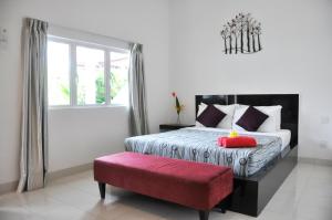 珍南海滩兰卡威尚提科酒店的一间卧室配有一张床和一张红色长凳