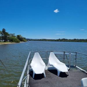 玛志洛The one & only Houseboat Hire on Maroochy River的两把白色椅子坐在船尾