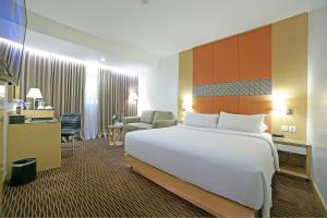 雅加达All Sedayu Hotel Kelapa Gading的酒店客房设有一张大床和一张书桌。