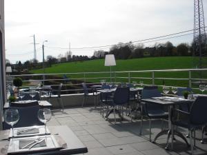 小勒尚乐米迪酒店的一个带桌椅的庭院和一个绿色的田野。
