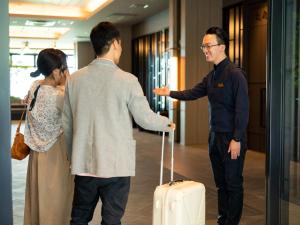 别府Grandvrio Hotel Beppuwan Wakura - ROUTE INN HOTELS -的男人和女人和男人说话,带着手提箱