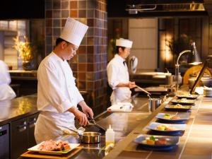 别府Grandvrio Hotel Beppuwan Wakura - ROUTE INN HOTELS -的两名厨师站在厨房准备食物