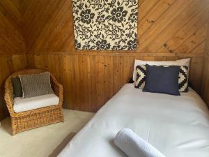 FalmouthWhite Shell Cottage - Woodfire & Beachfront的一间卧室配有一张大床和一把椅子
