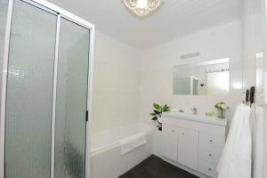 FalmouthWhite Shell Cottage - Woodfire & Beachfront的带淋浴和盥洗盆的白色浴室