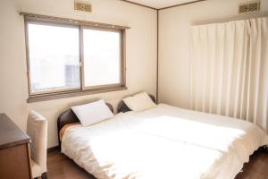 诹访市一組貸切宿 岡村 弐番館 一棟まるまる貸切的一间卧室设有两张床和窗户。
