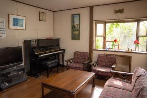 诹访市一組貸切宿 岡村 弐番館 一棟まるまる貸切的客厅配有钢琴、椅子和桌子