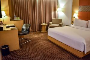 雅加达All Sedayu Hotel Kelapa Gading的配有一张床和一把椅子的酒店客房