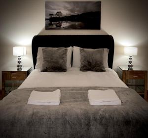 卢斯Lomond Castle Penthouse的一间卧室配有一张带两张桌子和两条毛巾的床。
