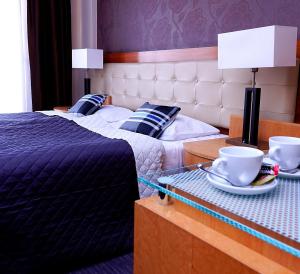 奥斯特罗达Platinum Ostróda的两张位于酒店客房的床,桌子上有杯子