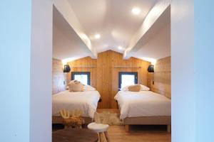 尚鲁斯L'Etincelle Mountain Lodge的木墙客房的两张床