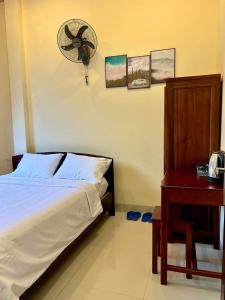 Ấp Bình HưngT's House Motel的卧室配有1张床、风扇和桌子