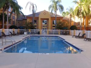 奥兰多SureStay Plus by Best Western Orlando Lake Buena Vista的棕榈树建筑前的游泳池