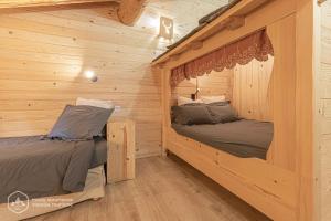 阿尔克河畔博讷瓦勒Chalet Le Bois Joli的小木屋卧室设有两张木墙床