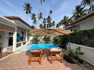 苏梅岛Holiday house near Lamai with swimming pool. 2 bedrooms的一个带桌子和遮阳伞的庭院,毗邻一个游泳池