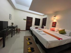 华欣Rainforest Huahin Village Hotel的配有钢琴和书桌的客房内的两张床