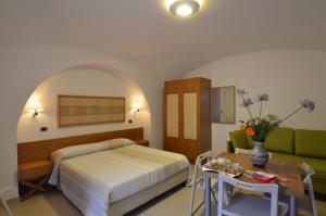 庞贝宙斯酒店的一间卧室配有一张床、一张桌子和一张沙发