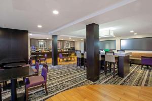 罗缪勒斯La Quinta Inn & Suites by Wyndham Detroit Metro Airport的酒店客房设有桌椅和酒吧