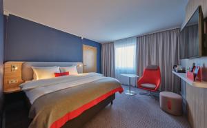 科隆Holiday Inn Express Cologne Mülheim, an IHG Hotel的酒店客房设有一张大床和一张红色椅子。