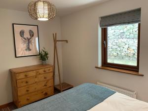 马根波思White Lodge - Coast Hideaways的一间卧室配有一张床、一个梳妆台和一扇窗户。