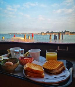 威尼斯Hotel Vecellio Venice on the Lagoon的托盘,包括烤面包、鸡蛋和橙汁