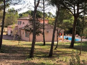 卡尔卡松Le Mas Victoria - Chambres d'hôtes avec table d'hôtes的粉红色的房子,设有游泳池和树木