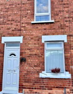 贝尔法斯特Stay-K-Belfast Cosy house 10 mins from city centre的砖砌建筑,设有两扇窗户和一扇白色门