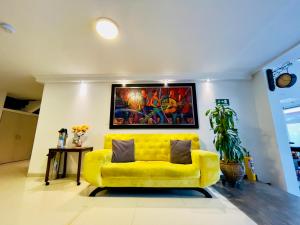 波哥大Hotel Santa Cruz Bogotá的客厅里一张黄色的沙发,墙上挂着一幅画