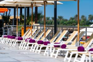 麦纳麦The Grove Resort Bahrain的庭院里一排带紫色靠垫的躺椅