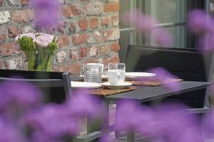 Frasnes-lez-AnvaingA Coque'Line的一张桌子,上面有盘子和玻璃杯,上面有紫色的鲜花