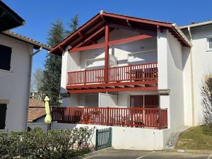 康博莱班Appartement Cambo-les-Bains, 2 pièces, 2 personnes - FR-1-495-4的白色的房子,设有红色栏杆阳台