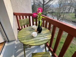 康博莱班Appartement Cambo-les-Bains, 1 pièce, 2 personnes - FR-1-495-31的阳台上的绿桌,花瓶上摆放着鲜花