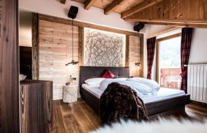 塞尔瓦迪加尔代纳山谷Garni Residence Soraiser的卧室配有一张床铺,位于带木墙的房间内
