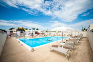 夏卡Bono Vacanze Villa San Marco Luxury Holidays Homes & Hotel的大楼内一个带椅子和遮阳伞的游泳池