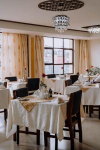 内罗毕萨博皇家酒店的餐厅设有白色的桌椅和窗户。