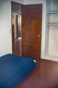 皮里亚波利斯Casa para 4 pers. con entrada de auto y parrillero的一间卧室设有木门和一张蓝色的床
