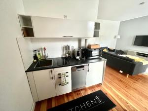 杜塞尔多夫Cityapartments Düsseldorf - Stresemannstraße的一间带白色橱柜的厨房和一间客厅